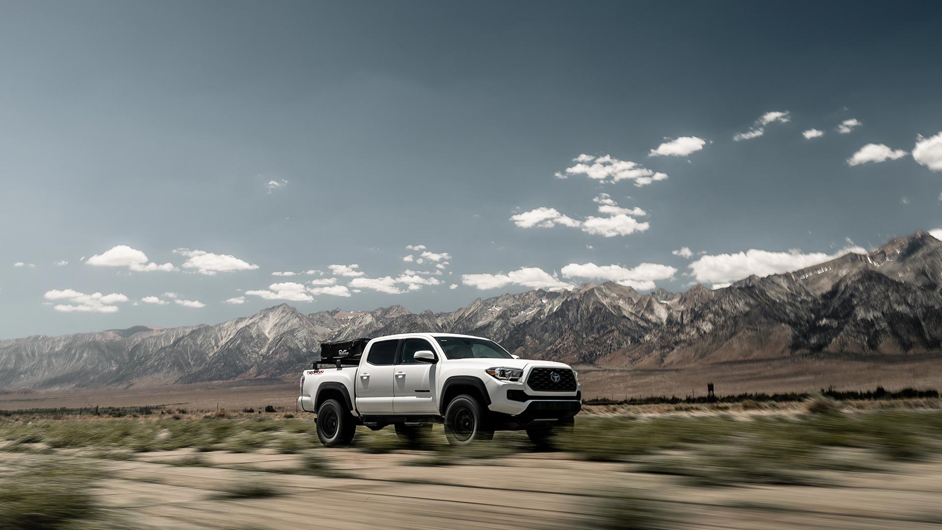 White Toyota Tacoma driving through a desert with RBP Repulsor M/T tires