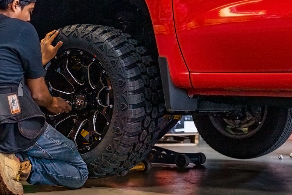 Image of a wheel technician changing tires on a red Chevy Silverado