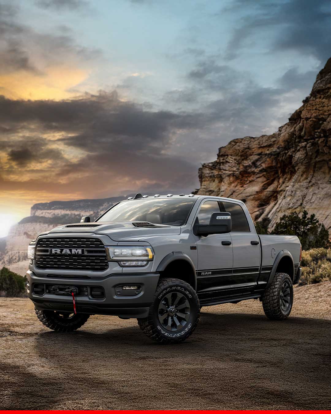 gray dodge ram 2500 with off road tires parked on dirt trail against dramatic mountain sunset